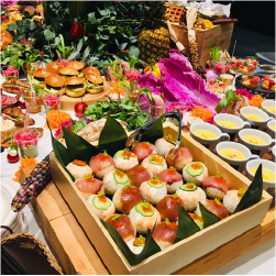 寿司や、ハンバーガーなどの色とりどりの料理やフルーツや野菜がテーブルに並んでいる画像